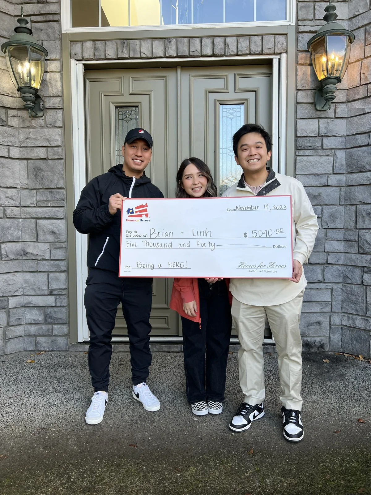 Homes for Heroes clients with Daniel Chin holding a reward check outside a home