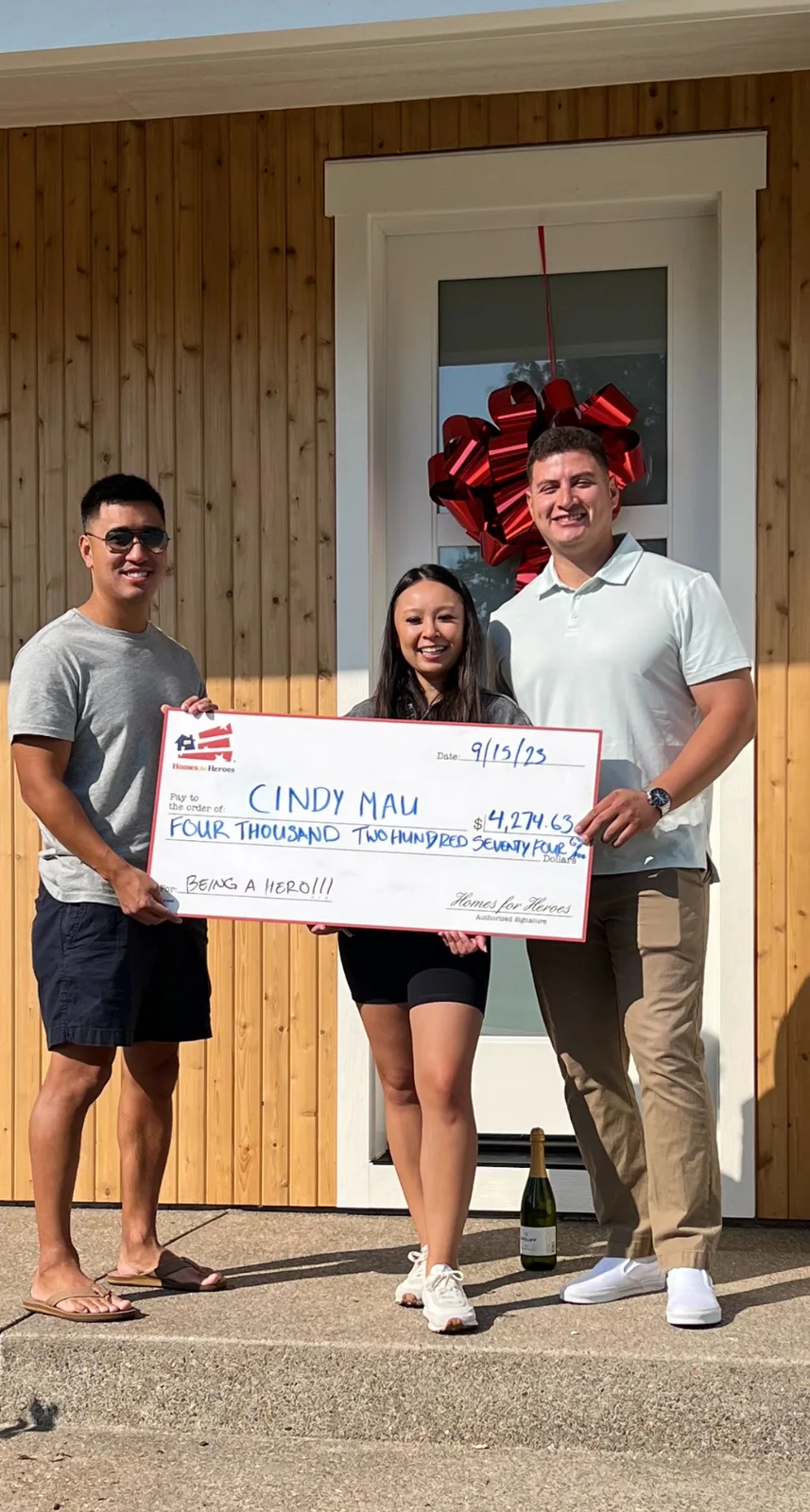 Homes for Heroes clients celebrating with a reward check in front of their home