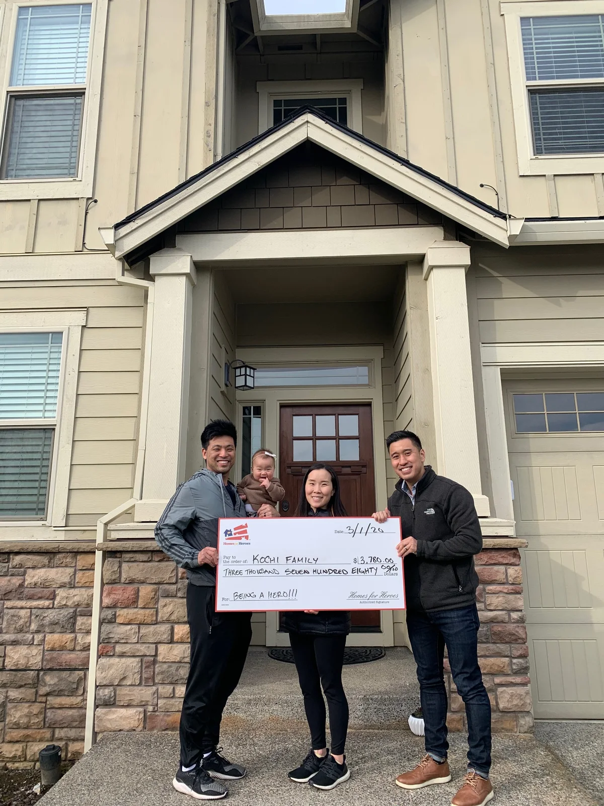 Daniel Chin with a family outside their home holding a Homes for Heroes reward check